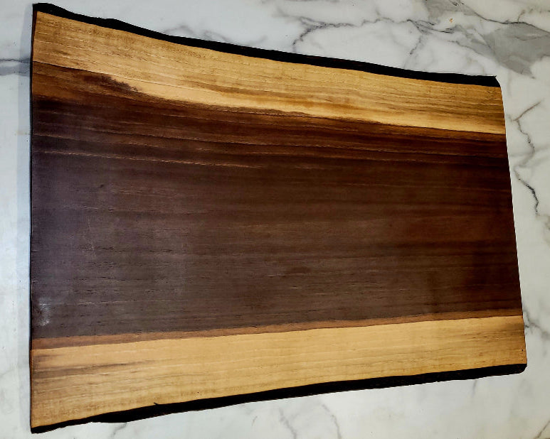 A live edge Black Walnut Grazing board. 
 Medium length, dark centre, with light coloured border, and black bark